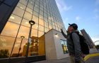 Individual looks up at tall glass building