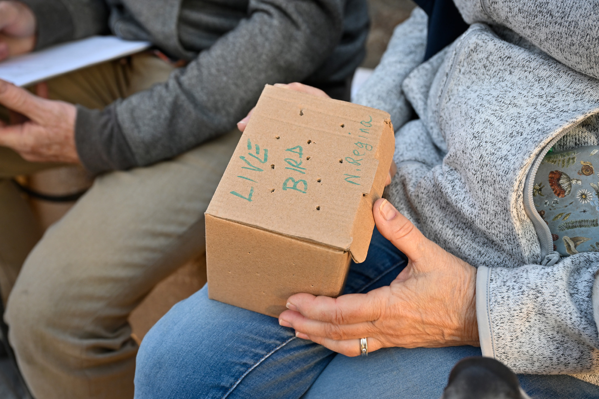 Bird box held in lap of invdividual.